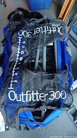 Black mesh Outfitter 300 cover or bag laid over blue background with visible branding and measurements.