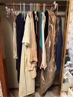 Image showing various clothing items hanging on hangers in a closet, including dresses and coats.