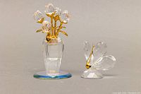 Both Swarovski crystal figurines side by side: potted tulip bouquet and butterfly on mirror base