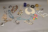 Top-down image showing the full layout of assorted necklaces and bangles for identification and condition review.