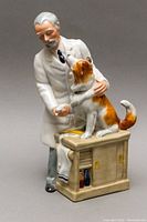 Front and side view of the Royal Doulton porcelain figurine showing the doctor shaking the dog's paw on the examination table.