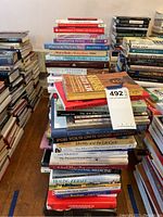 Stack of mixed hardcover and paperback books on floor against wall with visible titles on self-help, healing, spirituality and psychology.