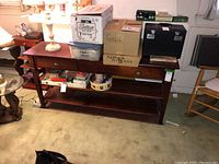Full front view of wooden credenza with various boxes and items set on top and under the shelving. Shows overall structure and drawer fronts.