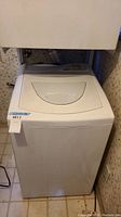 Full view of white Kenmore top load washing machine with lid closed, showing overall external condition and dimensions tag.