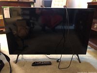 Front view of television on stand with power cord and remote in front