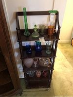 Frontal view of the vintage 5-tier wooden shelf showing the five shelves and turned wood columns, with various glass items on the shelves.