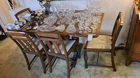 Overall view of wooden table with drop leaves and four chairs, glassware and accessories on tabletop not included