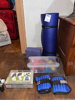 Photo shows full lot: blue rolled yoga mat with black BalanceFrom strap, blue Gaiam yoga block, clear plastic container with various small dumbbells, All Pro ankle weights pair with box.