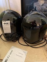 Two black AirFree air purifiers with power cords and instruction manuals placed on a floor in front of a fireplace.