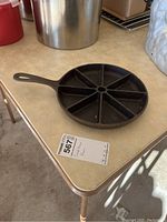 Cast iron cornbread skillet on countertop with visible seven wedge-shaped compartments and handle.