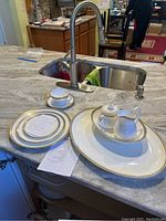 Set of plates, tea cups, sugar bowl, creamer and serving platter arranged on countertop