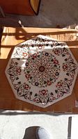Top view of the octagonal marble table top with intricate colorful stone inlay in floral patterns.
