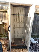 Front view of open outdoor storage cabinet showing double doors, interior floor, and built-in shelf supports.