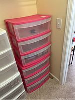 Two stacked red and clear plastic drawer storage units in an office closet area.