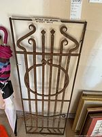 Full view of the antique New Orleans metal window grille showing ornamental scroll design and rusted metal surface.