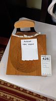 Wooden bowl with handwritten note 'Alaska - Very Sharp' and lot tag