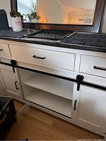 Front view of white wooden island with black metal barn door hardware and top folded down