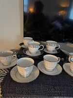 Eight Lenox bone china cups and saucers displayed showing different patterns with silver rims.