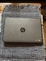 Closed HP Chromebook on dark blue woven mat showing HP logo and Chrome branding on lid.