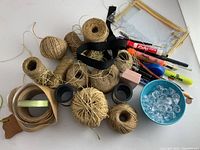 Top view of jute twine rolls, ribbons, writing supplies, and decorative crystals in a blue container