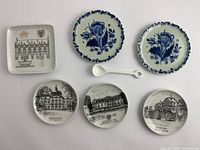 Six ceramic coasters and plates laid out, showing decorative patterns and cityscape scenes.