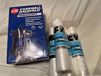Image of Campbell Hausfeld spray gun box next to four rolls of painter's plastic sheeting, 4' x 180' each.