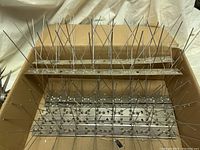 Seven metal bird deterrent strips showing rows of sharp spikes attached to a narrow metal base.