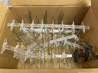 Box containing multiple bird deterrent strips with clear plastic bases and metal spikes along with some black plastic bases.