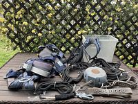 The full lot of climbing gear on a wooden surface outdoors, including harnesses, ropes, and a pulley device.