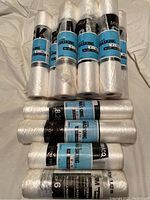 Photo showing eight rolls of plastic masking film, each 4 feet by 180 feet, with blue labels marked Trimaco Easy Mask.