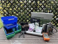 Wide shot of entire lot showing hydraulic bottle jack, tool bag, caulk dispenser, plastic containers, and other tools.
