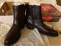 Pair of brown leather Laredo men's boots displayed standing outside box, showing front and inner side with zipper.