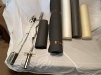 Photo showing Olympic curved barbell, Pilates chair sculpting handles, and rolled gym mats.