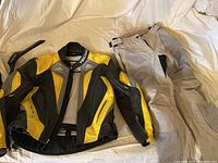 Yellow and black leather Teknic motorcycle jacket laid flat with visible zippered pockets and ventilation vents.