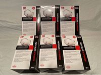 Six boxes of N95 valved particulate respirators displayed on a surface. Each box states it contains 10 masks.