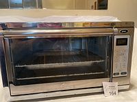 Front view of Oster stainless steel toaster oven with glass door and metal handle.