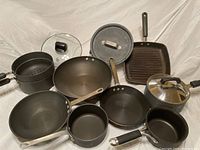 Overview of all cookware items including pots, pans, lids, and grill pan showing condition and set contents.