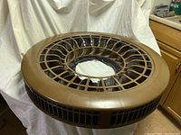 Top view of the round brown plastic air filter housing with grille sides and central airflow opening.