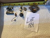 Photo showing all jewelry pieces including tie pin, cuff links, religious pendant, and small pins with measuring tape for size reference