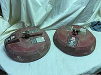 Two red circular surface washer attachments side by side, showing overall size and shape