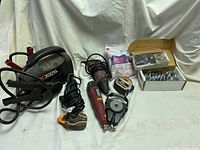 Overall view of multiple tools including Makita power drill 300XL, red handheld tool, 3M tape measure, and box of locks.