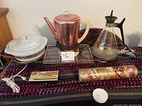 Full set of vintage kitchen items displayed including percolator, carafe, casserole dish, warming tray, corn butterer, and Magic Mop