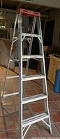 Full view of the aluminum 6 feet step ladder showing four steps and red top cap.
