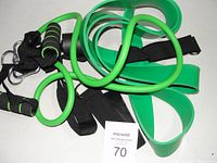 Image showing several green resistance bands including loop bands, bands with handles, and black adjustable ankle straps for fitness use.