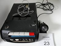 Sony cassette tape recorder with microphone and stand viewed from the front showing control buttons and part of microphone cable.