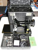 Open hard carrying case with sewing machine fitted inside and accessory tray in front