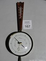 Full view of vintage 15-inch barometer with attached thermometer and wood backing, showing condition and design.