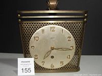 Front view of vintage Kaiser clock showing round clock face with gold-tone numerals and metal lattice frame.