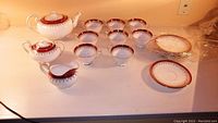 Overview of teapot, creamer, sugar bowl, eight teacups and eight saucers arranged on countertop