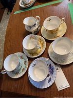 Top photo showing six Royal Albert tea cups and saucers, each with unique floral design and gold trim.